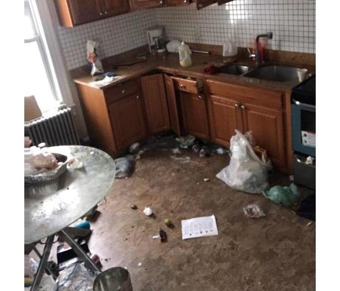 Kitchen with wooden cabinets and garbage on floor
