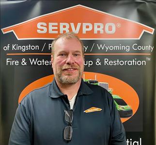 male employee in front of SERVPRO black and orange pop up sign
