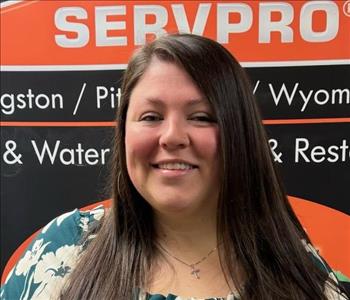 SERVPRO employee in front of a black and orange banner 