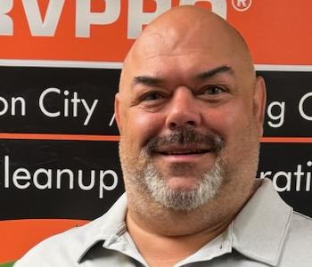 SERVPRO employee in front of a black and orange banner
