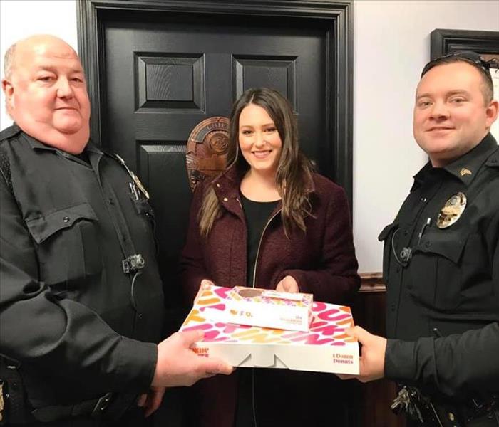 Marketing Manager with two police officers holding box of donuts