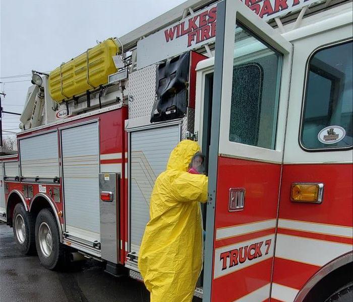 SERVPRO tech in yellow PPE cleaning red Wilkes-Barre Firetruck