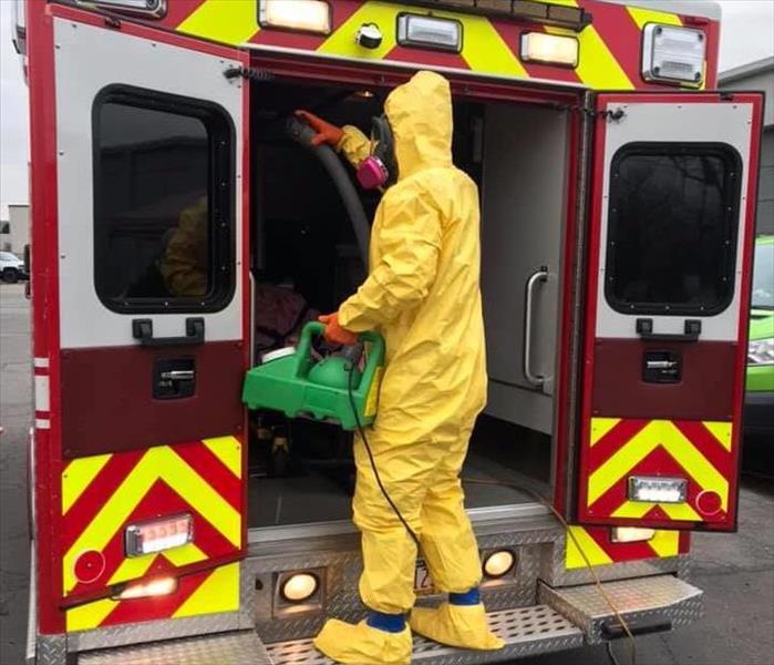 SERVPRO tech in yellow PPE cleaning red Kingston Ambulance
