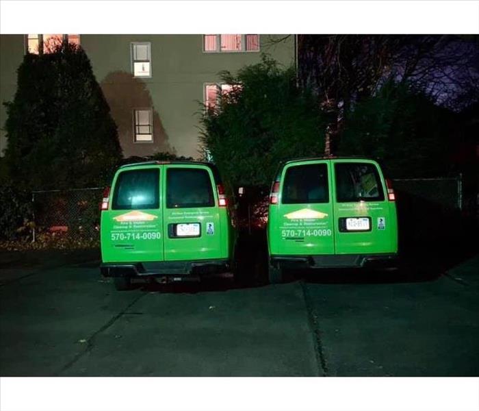 Two green SERVPRO Vans in parking lot at night time