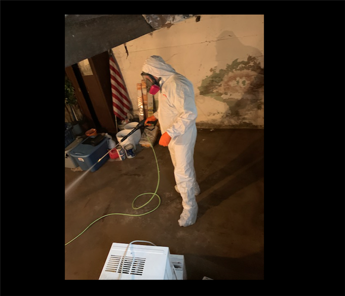 Technician dressed in white PPE in residential basement 