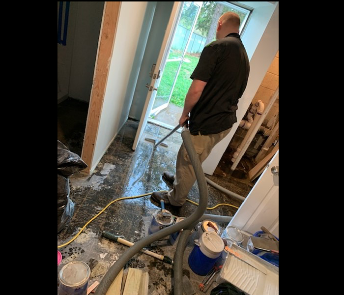 SERVPRO technician extracting water from grey flooring in residential home