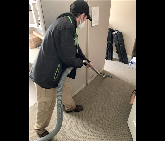 SERVPRO technician extracting water from light grey carpet