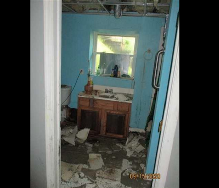 Water damage and debris in blue restroom 