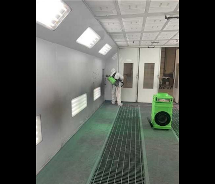 SERVPRO tech in white ppe cleaning white room with air scrubber in room 