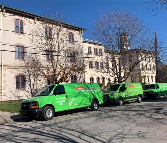 Three green SERVPRO trucks in front of commercial building 