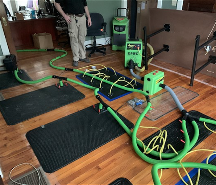 Green SERVPRO equipment on hardwood floors with black mats