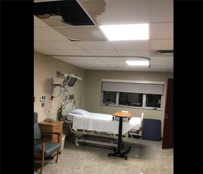 white hospital room with missing ceiling tiles from water damage 