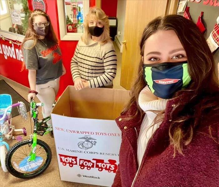 Three individuals with Toys for Tots box and bikes