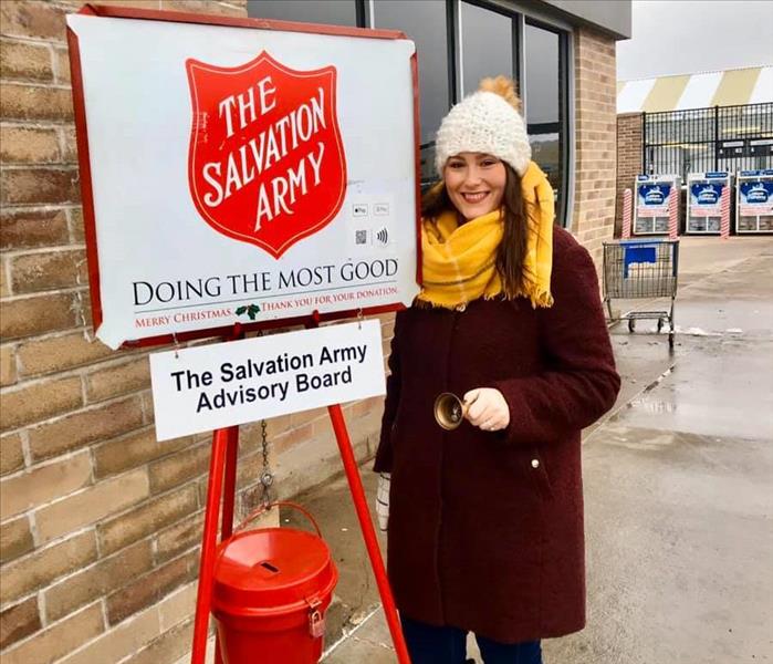 Woman in front of Salvation Army Advisory Board sign ringing bell